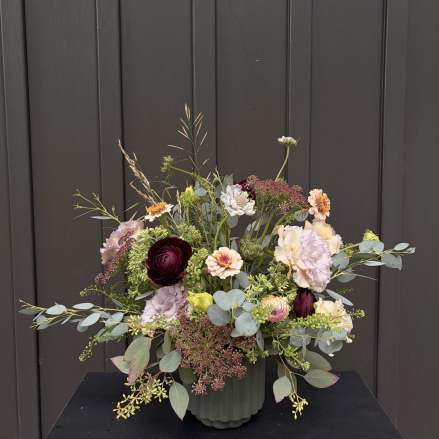 Mixed bouquet in a ribbed vase with burgundy, blush, and cream flowers