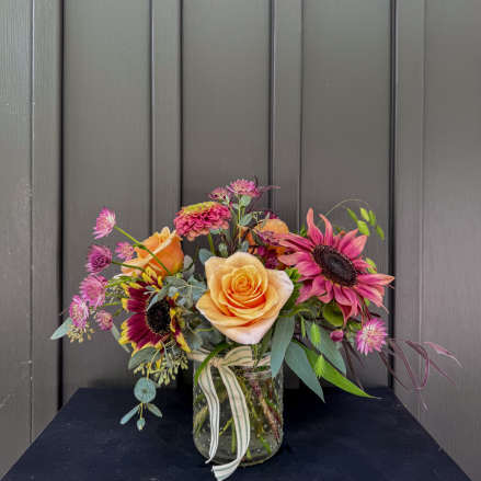 Mixed bouquet of roses and sunflowers in a glass jar vase