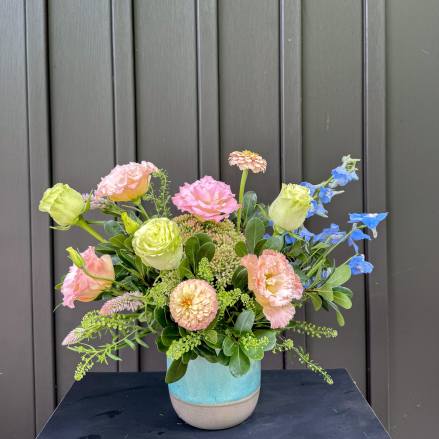 Pastel mixed flower arrangement in a blue ceramic vase