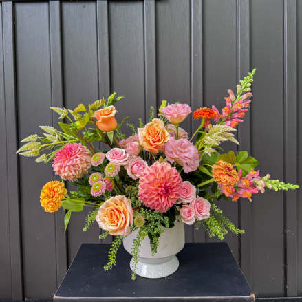 Mixed bouquet of pink, peach, and orange flowers in a white vase