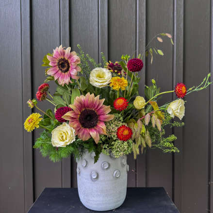 Mixed bouquet with sunflowers and white blooms in a gray vase