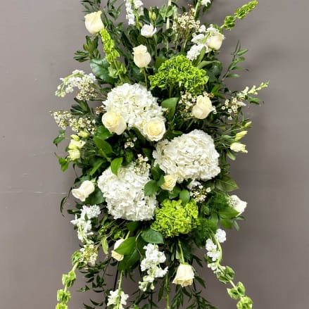 Tall standing spray of white roses and hydrangeas with green accents on an easel stand