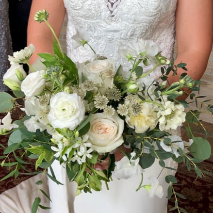 Bridal hand-tied bouquet of white and ivory roses with soft greenery accents.