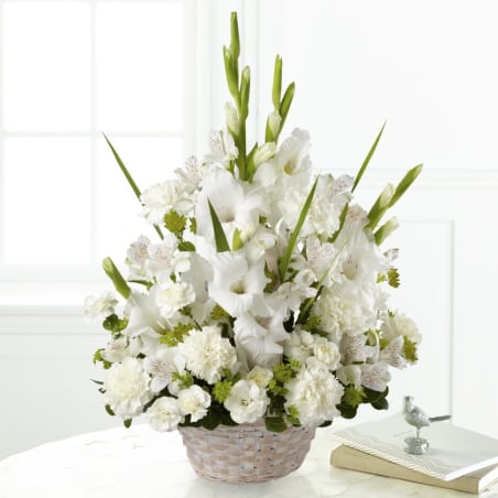 White floral arrangement in a woven basket with tall green spikes