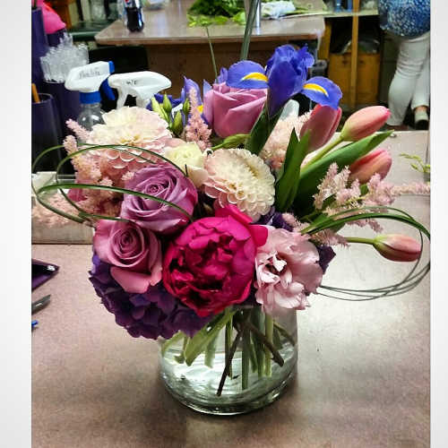 Mixed bouquet in a clear glass vase with roses, tulips, and irises
