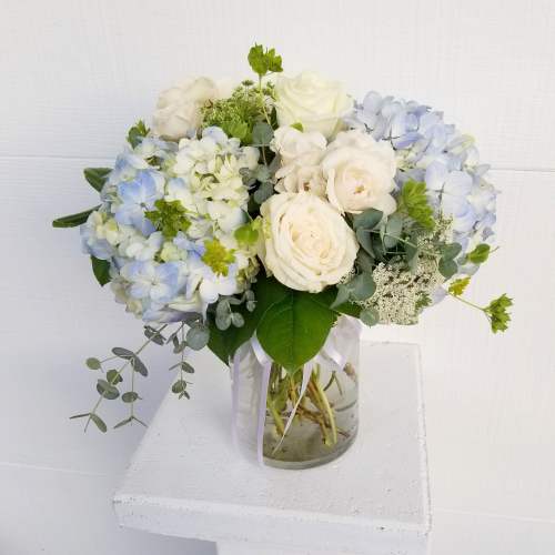 White and pale blue flower bouquet in a glass vase
