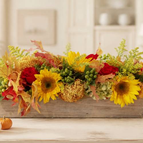 Autumn floral centerpiece with sunflowers and red roses in a wooden box