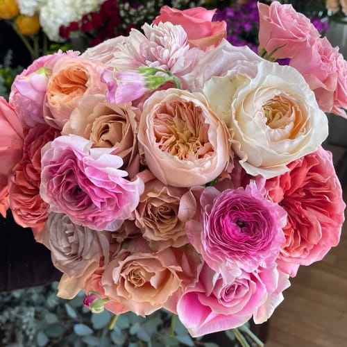 Hand-tied bouquet of pink, peach, and cream roses and ranunculus.
