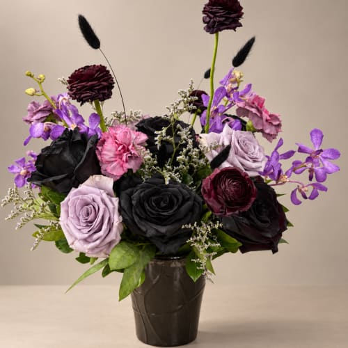 Bouquet of dark roses and purple flowers in a black vase