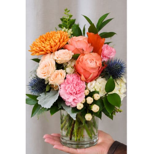 Mixed bouquet of orange, pink, and white flowers in a glass vase