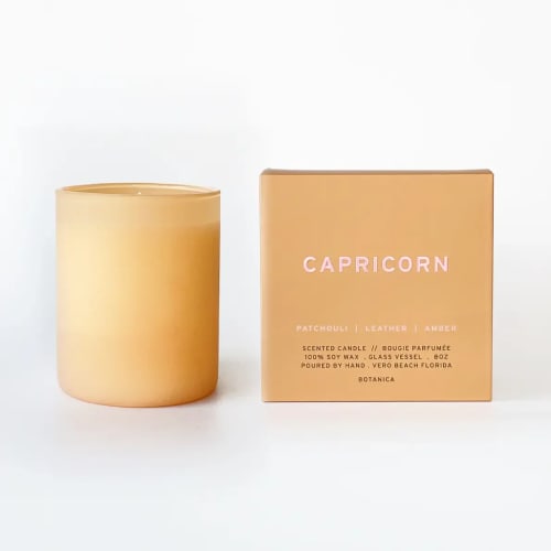 Beige scented candle in a glass vessel beside a matching box