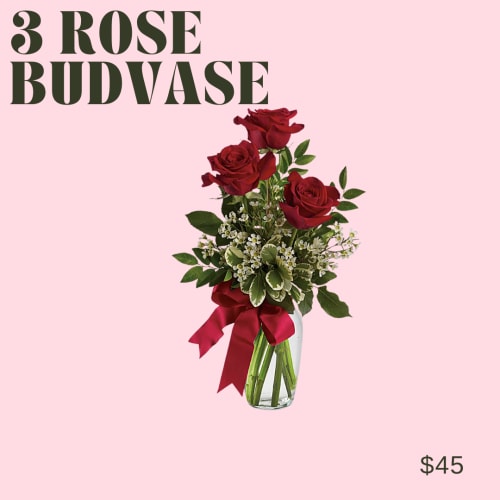 Three red roses in a clear glass vase with a red ribbon