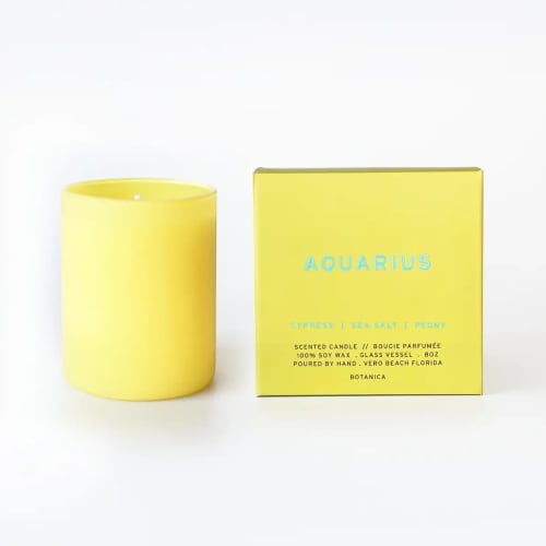 Yellow scented candle beside its matching box
