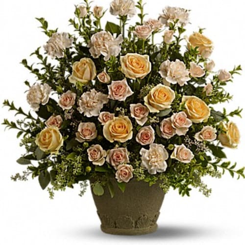 Cream and peach roses arranged in a low urn-shaped vase