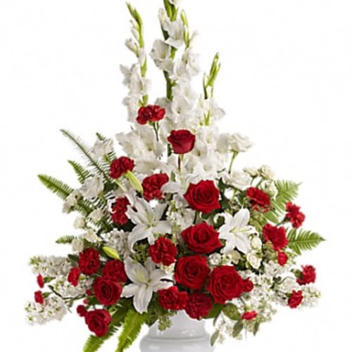 Tall red and white floral arrangement in a white pedestal vase
