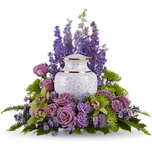Purple floral arrangement around a white urn vase