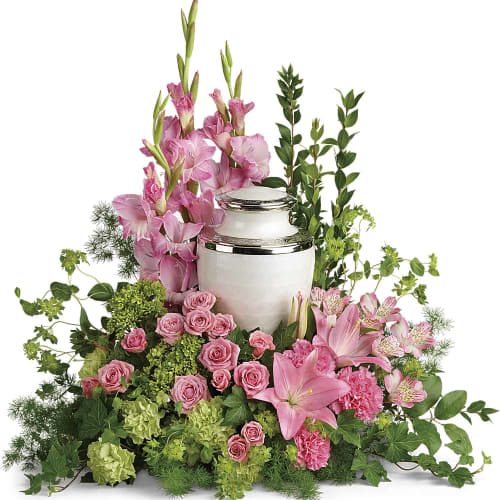 Pink floral arrangement around a white urn with silver trim