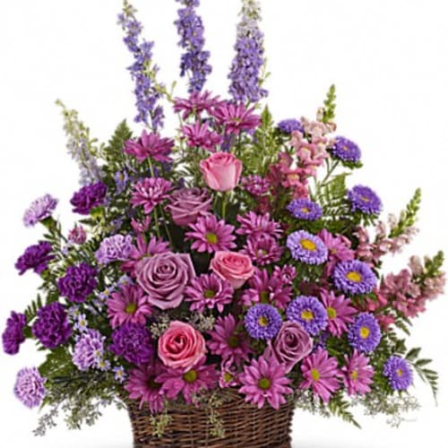 Purple and pink mixed flower arrangement in a wicker basket