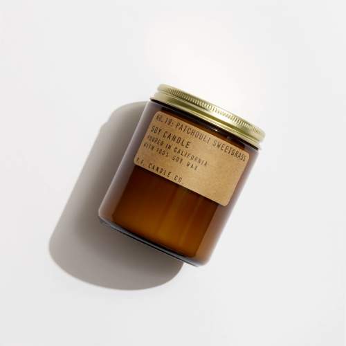 Amber glass candle jar with a gold lid and paper label