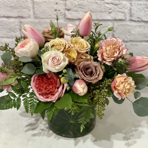 Pink and peach roses with tulips in a dark glass vase