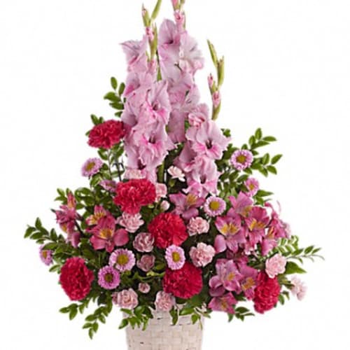 Pink floral arrangement in a woven basket with tall blooms and carnations