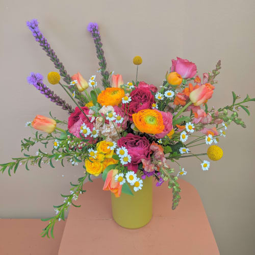 Colorful mixed bouquet in a yellow vase with roses, tulips, and daisies
