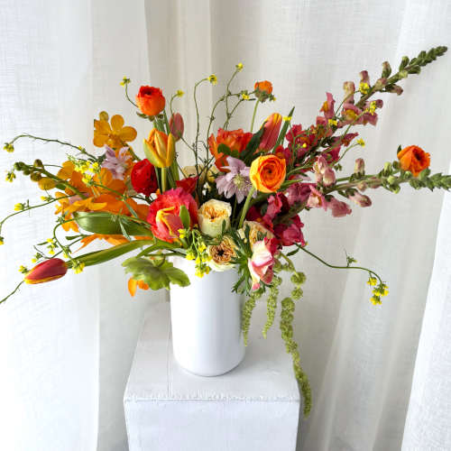 Mixed bouquet in a white vase with orange, pink, and yellow flowers