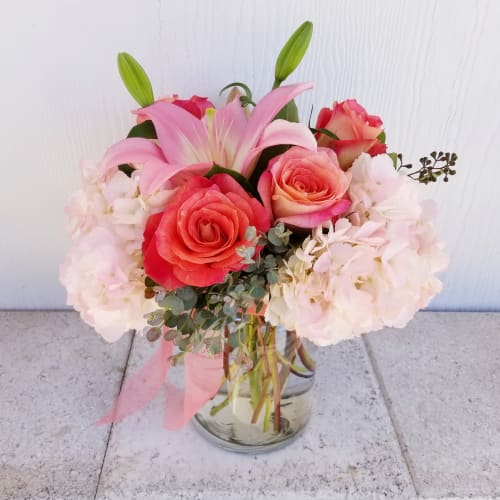 Pink lilies and roses arranged in a glass vase