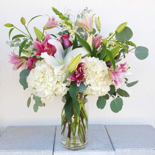 Bouquet of pink lilies, white hydrangeas, and eucalyptus in a glass vase