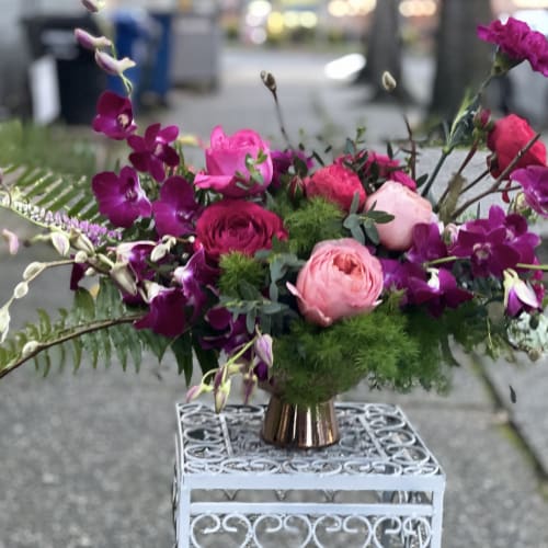 Pink and purple floral arrangement in a small copper vase
