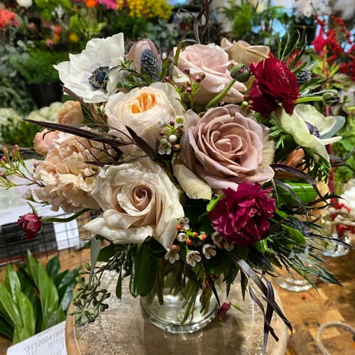 Mixed bouquet of roses, poppies, and carnations in a glass vase
