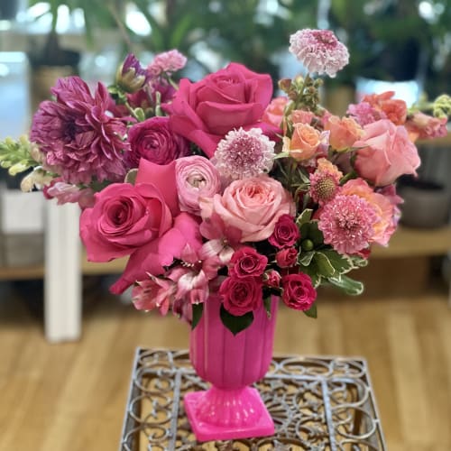 Pink and peach mixed flower arrangement in a bright pink vase