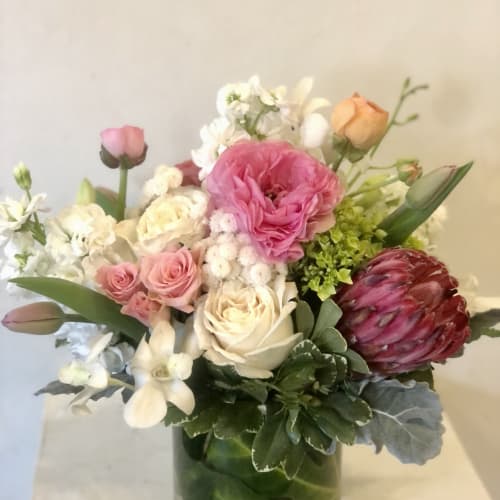 Mixed bouquet of pink, white, and peach flowers in a glass vase