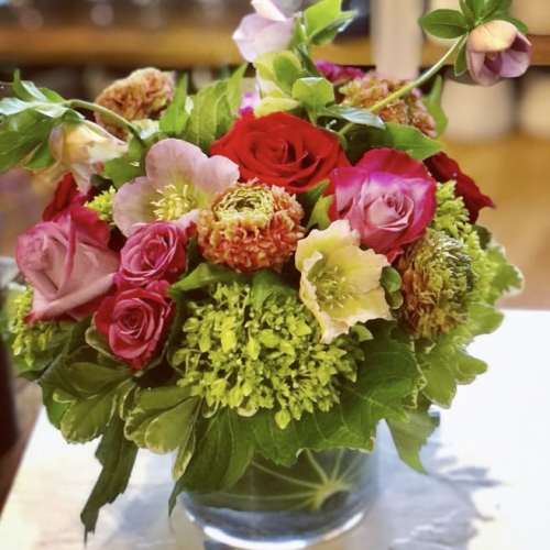 Mixed bouquet of roses and green blooms in a clear glass vase