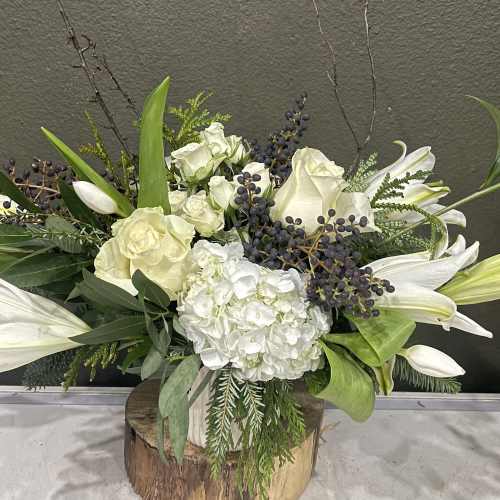 White lilies and roses arranged in a wooden vase