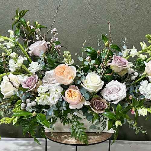 Large pastel floral arrangement with roses and white blooms in a low container