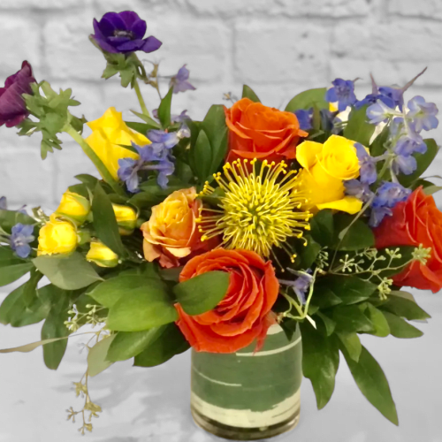 Colorful bouquet of roses and blue flowers in a glass vase