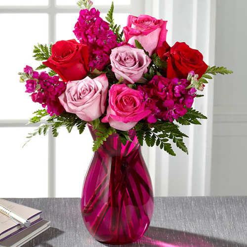 Bouquet of pink and red roses in a magenta glass vase