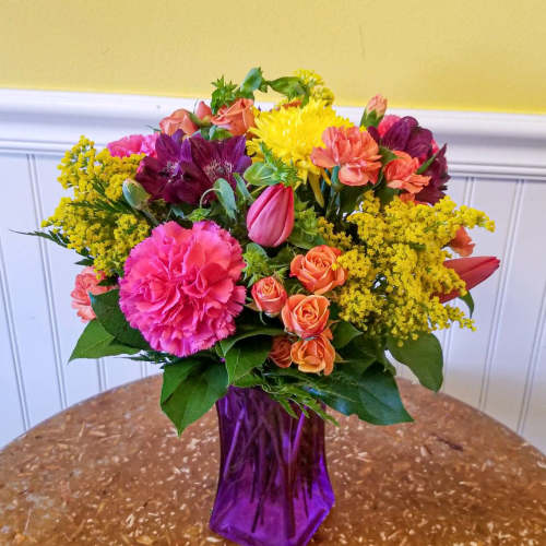 Colorful mixed bouquet in a purple glass vase
