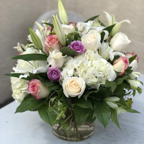 Mixed bouquet of white and pink roses with lilies in a glass vase