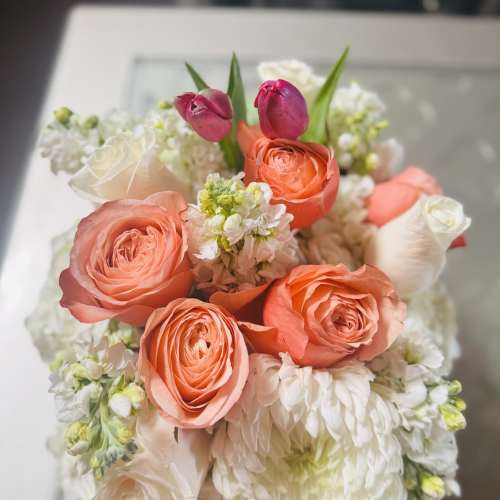 Bouquet of coral roses, white blooms, and pink tulips