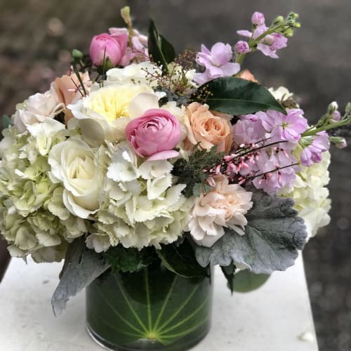 Pastel bouquet of roses, hydrangeas, and ranunculus in a glass vase