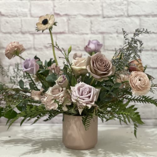 Pastel bouquet of roses and ranunculus in a blush ceramic vase