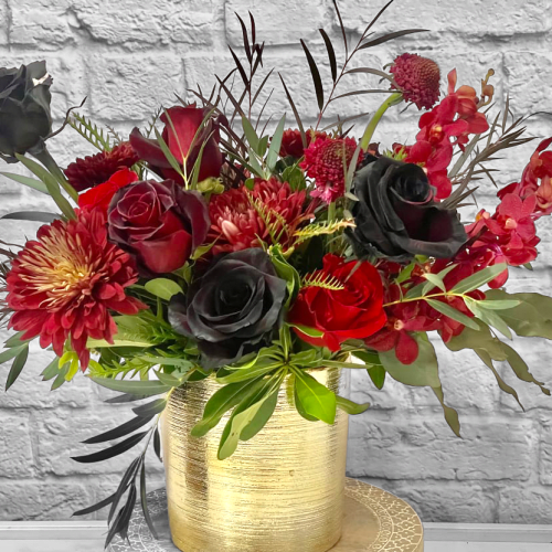 Red and black floral arrangement in a gold vase