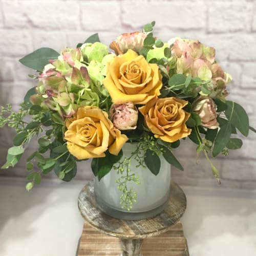 Yellow roses and pale hydrangeas in a glass vase