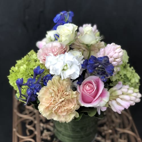 Mixed bouquet of pink, white, and blue flowers in a green vase