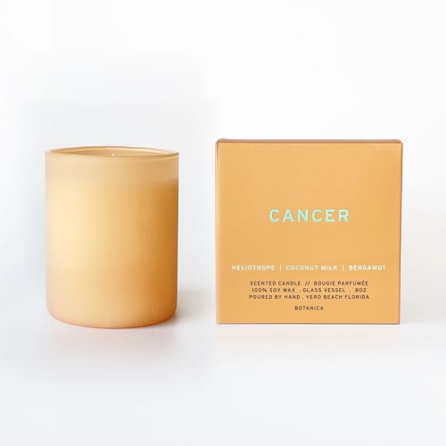 Amber scented candle beside a matching box labeled Cancer