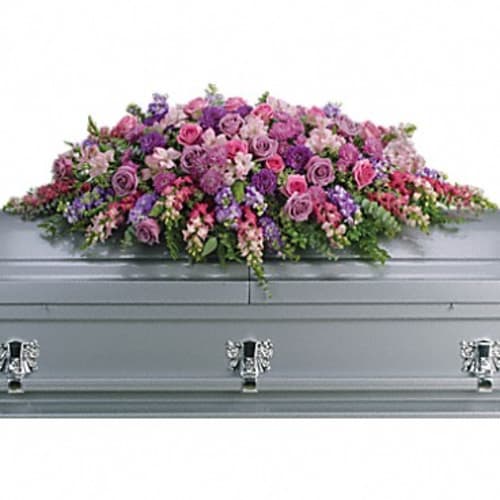 Pink and purple floral casket spray on a gray casket