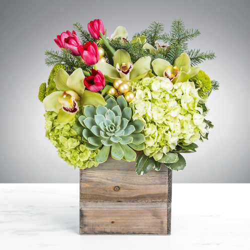 Green hydrangeas, orchids, pink tulips, and a succulent in a wooden cube vase