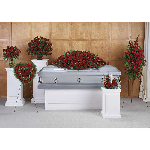 Casket surrounded by red rose funeral sprays and wreaths